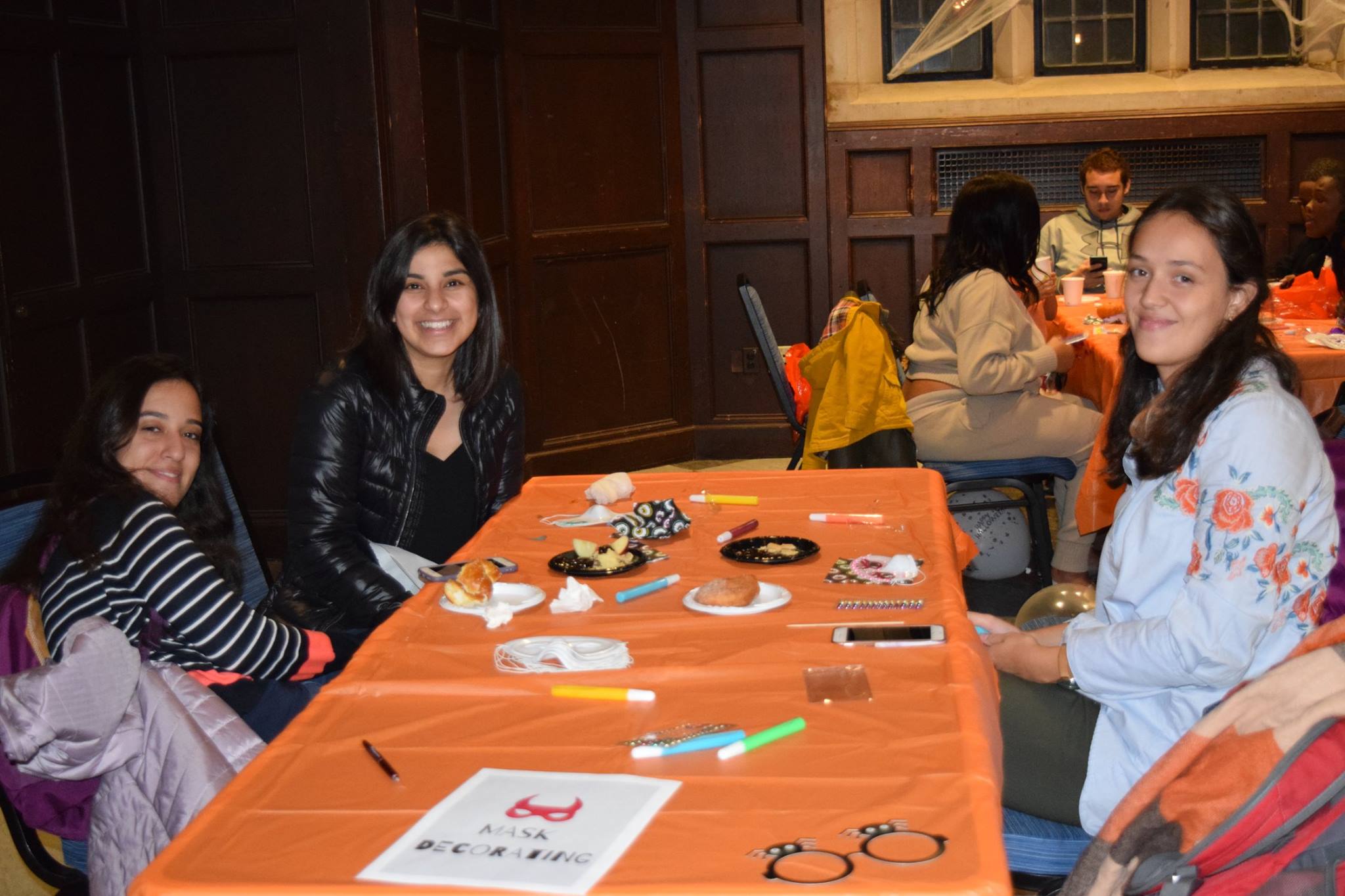Penn Students decorating Halloween masks at a table together and enhoying the festivities