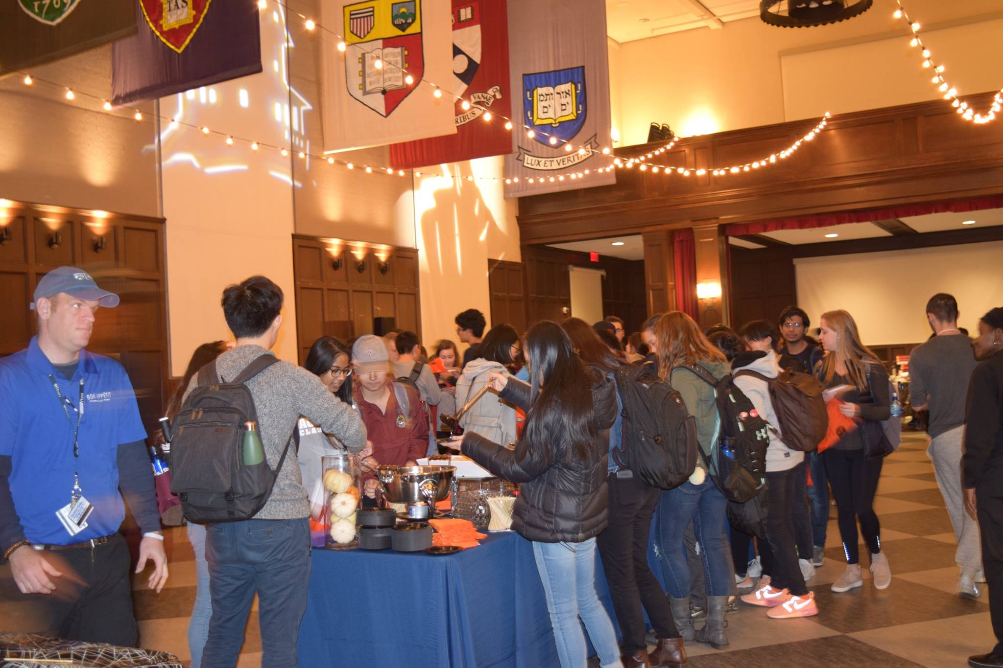 Penn Students gather in the Houston Hall of Flags around a banquet table loaded with Halloween sweets