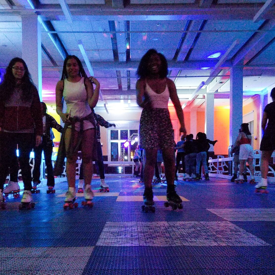 Students roller skating on the pop up roller rink set up in Bodek Lounge